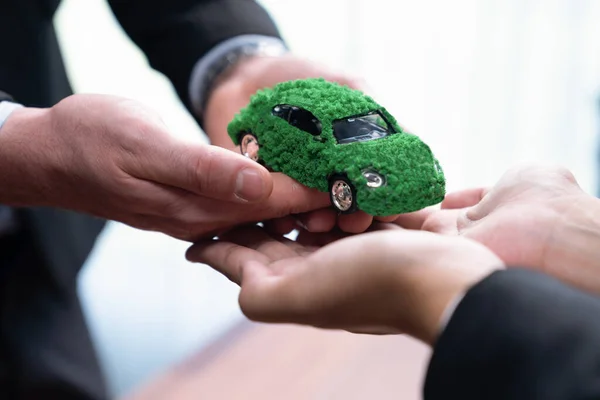 Business people exchange and holding green eco car model. Electric vehicle utilized by eco-friendly company for environmental friendly transportation. Zero CO2 emission corporate responsible. Quaint