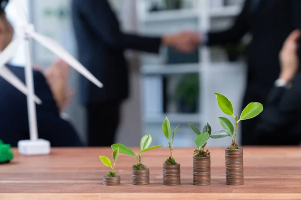 Organic money growth investment concept shown by stacking piles of coin with sprout or baby plant on top. Financial investments rooted and cultivating sustainable clean energy with nature. Quaint