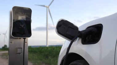 Çevreyi korumak için rüzgar türbininden yeşil ve yenilenebilir enerjiyle çalışan şarj istasyonunda şarj edilen gelişmiş gelecek enerji altyapısı konsepti.