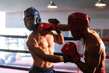 Kasklı iki atletik ve kaslı vücut boksörü ya da boks baş muhafızı vahşi bir boks maçında karşı karşıya. Boks dövüşçüsü boks ringinde dövüşüyor. Impetus