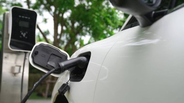 Yakın çekim yenilikçi modern ulaşım konsepti, elektrikli araba şarj istasyonunda gökyüzünden yansıyan yüksek detay ile şarj ediliyor. Yenilenebilir enerji tarafından kullanılan çevre dostu elektrikli araç.