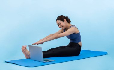 İnternetteki videodan alınan talimatlara göre spor kıyafeti giymiş genç Asyalı bir kadın spor egzersizinden önce geriniyor. Sağlıklı atletik bir kadınla vücut egzersizi izole bir zeminde ısınıyor. Kuvvetli