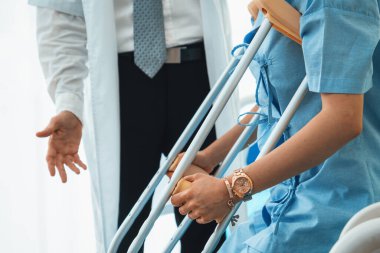 Doktor hastanede koltuk değnekli hastayla ilgileniyor. Fizyoterapist ve bacak yaralanması konsepti. Jivy