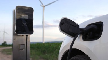 Çevreyi korumak için rüzgar türbininden yeşil ve yenilenebilir enerjiyle çalışan şarj istasyonunda şarj edilen gelişmiş gelecek enerji altyapısı konsepti.