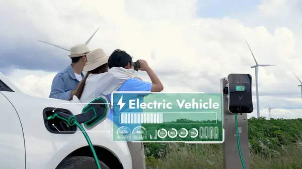 Modern family travel and nature with eco-friendly EV car concept, display digital battery recharging status hologram using renewable energy from wind turbine for future energy sustainability. Peruse