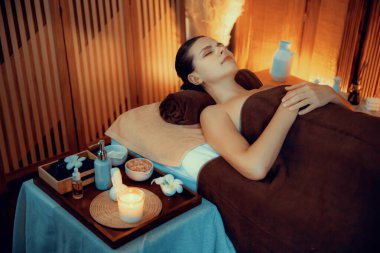 Beyaz kadın müşteri stres önleyici spa masajının keyfini çıkarıyor ve lüks otel ya da otelde sıcak mum ışığında güzellik teniyle eğleniyor. Sessiz.