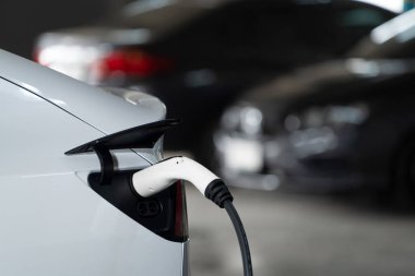 Alış veriş merkezinin otoparkında EV elektrikli araba şarjı şehir merkezindeki sürdürülebilirlik yaşam tarzını yeşil, temiz, yeniden şarj edilebilir elektrikli araç iç organları ile gösteriyor.