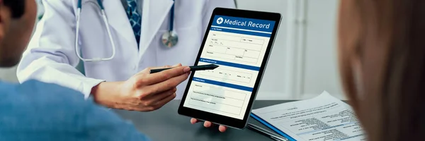 Doctor show medical diagnosis report on tablet and providing compassionate healthcare consultation to young couple patient in doctor clinic office. Medical appointment and healthcare concept. Neoteric
