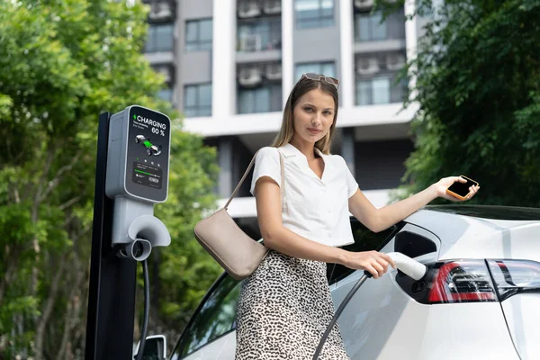 Młoda Kobieta Podróżuje Ładowania Samochodów Elektrycznych Zielonym Zrównoważonym Ogrodzie Miejskim — Zdjęcie stockowe