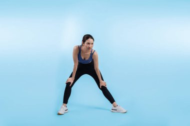 Spor giyim portresindeki tüm vücut Asyalı kadın gülümsüyor ve neşeli bir jest yapıyor. Çekici bir kızla egzersiz yapmak sağlıklı yaşam tarzını sürdürmeye yöneliktir. İzole edilmiş arka plan Vigorous