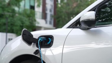 Elektrikli araba, gelecekteki ev şarj istasyonunda akıllı dijital EV batarya durumu hologramıyla şarj oluyor. EV arabasının teknolojik gelişimi ve sürdürülebilir gelecek için ev enerjisi altyapısı. İncelenme