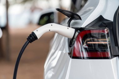 Kapalı EV şarj kolu fişe takıldı veya elektrikli arabaya bağlandı, EV araba aküsünü temiz çevre için sıfır CO2 emisyonu ile alternatif ve sürdürülebilir enerjiyle şarj etti. Kalıcı