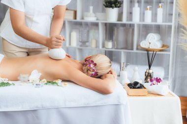 Sıcak bitkisel top spa masaj vücut tedavisi, masör kadın vücuduna nazikçe şifalı bitki torbası bastırıyor. Aromaterapi dinlenme sükuneti ve sükuneti kaplıca salonundaki atmosferi aydınlatıyor. Sessiz.