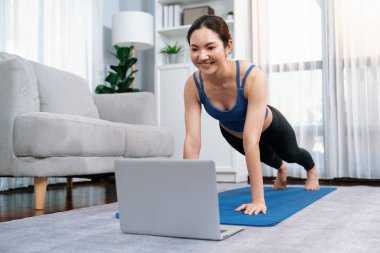 Çevrimiçi egzersiz videosundaki alıştırma talimatlarını takip ederken enerjik Asyalı kadın şınav çekiyor. Formda vücut arayışı ve uzak online antrenmandan sonra evde sağlıklı bir yaşam tarzı. Kuvvetli