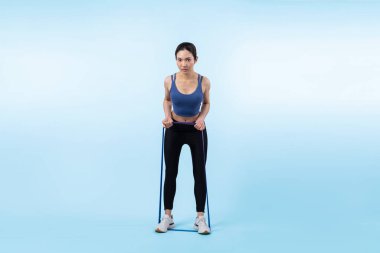 Spor giyim portresi giymiş enerjik bir kadın direnç sporu bandını geriyor. Genç atletik Asyalı kadın dayanıklılığı ve dayanıklılık eğitimi rutin konsepti tecrit edilmiş arka plan üzerine.