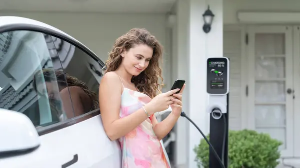 Ev充電ステーションから電気自動車を充電する現代の環境に優しい女性 エネルギー使用量を追跡するためのEv技術の活用は 家庭でのバッテリー充電を最適化します パノラマシンクロノス — ストック写真