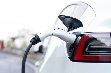 Kapalı EV şarj kolu fişe takıldı veya elektrikli arabaya bağlandı, EV araba aküsünü temiz çevre için sıfır CO2 emisyonu ile alternatif ve sürdürülebilir enerjiyle şarj etti. Kalıcı