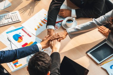 Mutlu iş adamları takım çalışmasının başarısını kutlarken ofis masasında yukarıdan çekilen neşeyle kutluyorlar. Genç işadamı ve işkadını işçiler, neşeli zafer gösterisi birliği desteği gösterdiler. Jivy