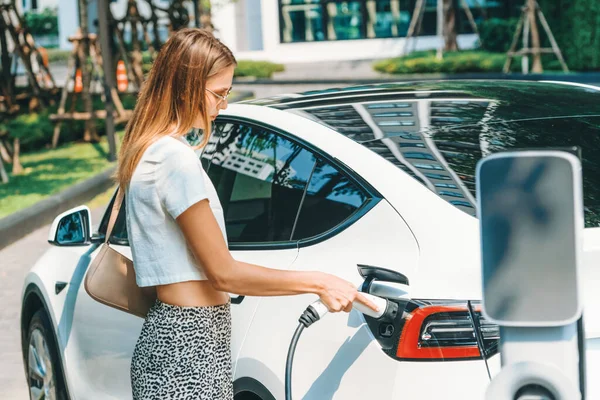 Νεαρή Γυναίκα Ταξιδεύουν Ηλεκτρικό Αυτοκίνητο Φόρτισης Στο Πράσινο Βιώσιμη Πόλη — Φωτογραφία Αρχείου