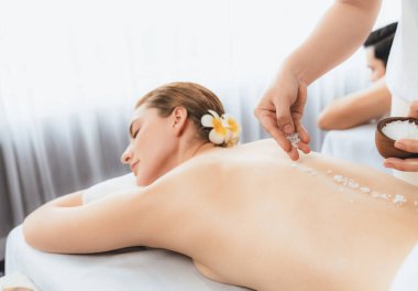 Lüks spa salonlarında sıcak mum ışığında cilt bakımı gören mutlu çift müşterisi. Sağlık kaplıcasında güzellik tedavisiyle tuz temizliği. Sessiz.