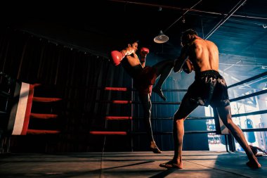 Asyalı ve Kafkasyalı Muay Thai boksörü boks antrenmanında diz atağı yapıyor, antrenörlerine diz vuruşu yapıyor, Muay Thai boks tekniği ve becerilerini sergiliyor. Impetus