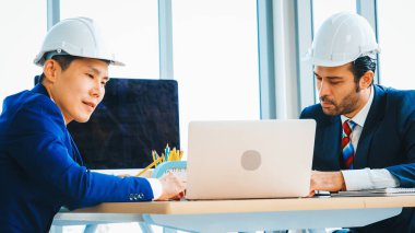 Mühendis ve mimar, mühendislik ve mimari proje planlaması hakkında ofis masasında toplanıyorlar. Jivy