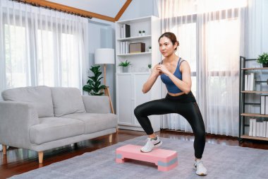 Enerjik bir kadın evde egzersiz yapıyor, kardiyo aerobik egzersizi yapıyor. Genç atletik Asyalı kadın mahareti ve dayanıklılık antrenmanı ev ödevi rutin konsepti olarak..