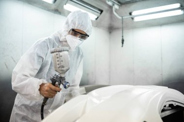 Tam korumalı ekipmanlı otomotiv işçisi sprey tabanca ya da oda atölyesindeki solunum cihazı boyasıyla araba kaportasına ustalıkla renk boyası uygular. Tamir için araba boyama servisi. Oxus.