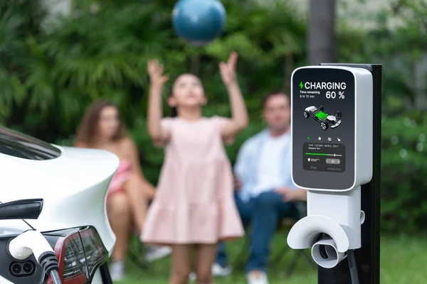 自宅の充電ステーションから電気自動車の充電に焦点を当て 幸せで遊び心のある家族が一緒に遊んでいます よりよい未来のための代替および持続可能なエネルギーを使用するEv車 シンクロノス — ストック写真