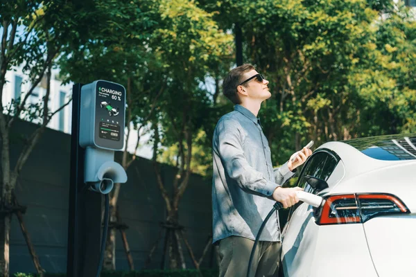 여름에 가능한 정원에서 자동차 남자는 자동차 내부의 깨끗한 충전식 에너지로 — 스톡 사진