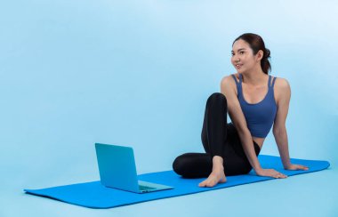 İnternetteki videodan alınan talimatlara göre spor kıyafeti giymiş genç Asyalı bir kadın spor egzersizinden önce geriniyor. Sağlıklı atletik bir kadınla vücut egzersizi izole bir zeminde ısınıyor. Kuvvetli