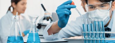 Kendini adamış bir grup bilim adamı tıbbi laboratuvarda kimyasal deney yapıyor. Aşı ilacı veya antibiyotik geliştirmek için pipetten deney tüpüne kesin miktarda sıvı döküyorlar. Neoterik