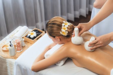 Sıcak bitkisel top spa masaj vücut tedavisi, masör kadın vücuduna nazikçe şifalı bitki torbası bastırıyor. Aromaterapi dinlenme sükuneti ve sükuneti kaplıca salonundaki atmosferi aydınlatıyor. Sessiz.