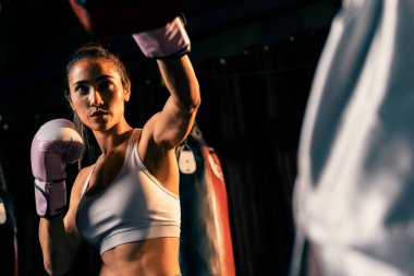 Asyalı kadın Muay Taylandlı boksör boks antrenmanını yumrukluyor idman antrenörüne boks eldiveni takıyor, Muay Tay boks tekniği ve becerisi sergiliyor. Impetus