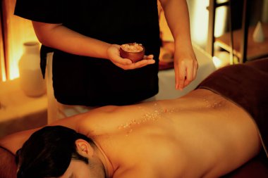 Lüks spa salonunda sıcak mum ışığı atmosferi olan deri dökülmesi tedavisi gören bir adam. Sağlık Spa vücut fırçasında tuz temizleme güzellik tedavisi. Sessiz.