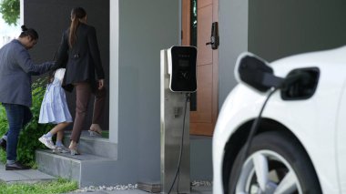 Elektrikli araç şarj istasyonu olan, sağlıklı ve temiz bir çevreyi teşvik eden yenilikçi bir aile kavramı. Sürdürülebilir, temiz enerji teknolojisiyle çalışan elektrikli araç..
