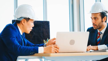 Mühendis ve mimar, mühendislik ve mimari proje planlaması hakkında ofis masasında toplanıyorlar. Jivy