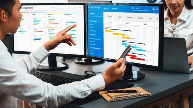 Projeyi koordine eden ve güncelleyen proje ekibi Gantt çizelge yazılımını kullanarak bilgisayarda program planladılar. Şirket işi için zaman ve süre belirleyen iş adamları. Önde.