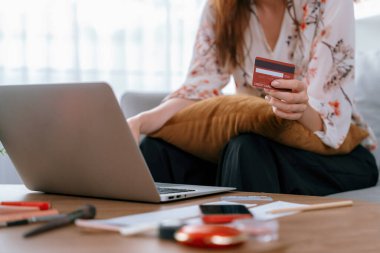 Genç mutlu kadın internetten alışveriş yaparak ürün satın alırken aynı zamanda internet üzerinden online ödeme sistemi ile çevrimiçi mağaza platformundan en yüksek siber güvenlik tarafından korunan ürünler sipariş ediyor.