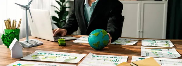 Businessman or CEO of the green corporate company holding paper Earth as concept for environmental friendly business to reduce CO2 emission and carbon footprint for cleann ecology. Trailblazing