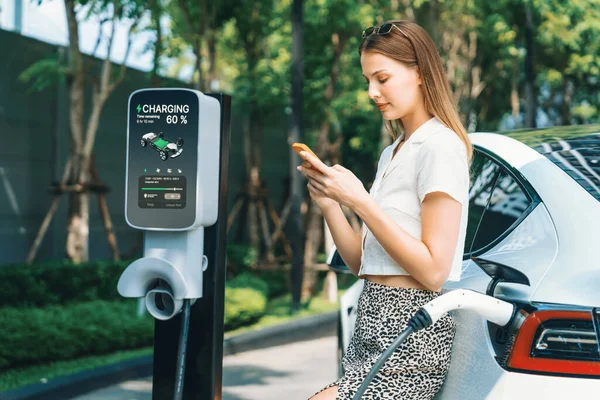 年轻女子乘坐电动车在绿色可持续城市室外花园充电 电动车内置车绿色清洁充电能的城市可持续生活方式 — 图库照片