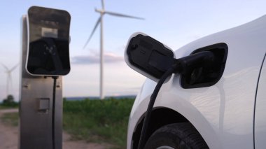 Çevreyi korumak için rüzgar türbininden yeşil ve yenilenebilir enerjiyle çalışan şarj istasyonunda şarj edilen gelişmiş gelecek enerji altyapısı konsepti.