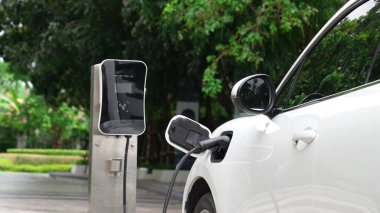 Elektrikli araba parkı ve şarj istasyonunun yanında şarj edilen enerji konseptinin sürdürülebilirliği. Çevresel koruma için yenilenebilir enerji tarafından kullanılan elektrikli araç.