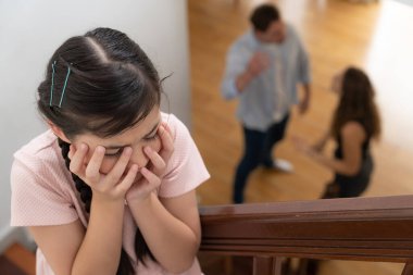 Stresli ve mutsuz genç kız merdivenden ebeveyninin tartışmasıyla ses gerilimini engellemek için kulaklarını kapatıyor. Sağlıksız aile ve aile içi şiddet travmatik çocukluk ve anksiyeteye yol açar. Eşzamanlama