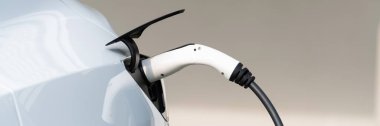 Elektrikli araç portuna bağlı EV şarj prizi kolu şarj istasyonundan şarj oluyor. Modern tasarlanmış EV araba ve daha iyi bir gelecek için temiz enerji sürdürülebilirliği. Panorama Senkronları