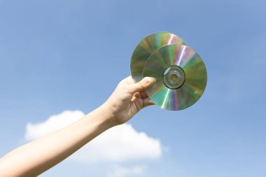 Geri dönüşümlü CD disk veya elektrik atığı gökyüzü arka planında el ele tutulur. Geri dönüşüm için elektronik çöpleri tutmak geri dönüşüm yönetimi ile temiz çevreyi geliştirmek için konsepti azaltmak ve yeniden kullanmak. Döngü