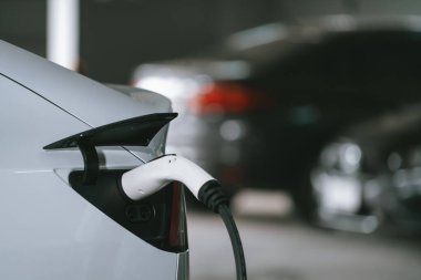 Alış veriş merkezinin otoparkında EV elektrikli araba şarjı şehir merkezindeki sürdürülebilirlik yaşam tarzını yeşil, temiz, yeniden şarj edilebilir elektrikli araç iç organları ile gösteriyor.