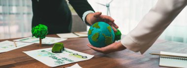 İş adamları ofis masasında kağıt toprağı bir arada tutuyorlar. Yeşil şirket CO2 emisyonunu azaltmak ve yeşil çevre kavramını korumak için çevre dostu politika uyguluyor. Önde.