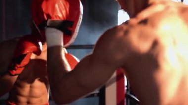 Asyalı ve Kafkasyalı Muay Thai boksörü boks antrenmanında boks antrenmanında boks antrenörüne yumruk atma, Muay Thai boks tekniği ve becerilerini sergileme. Impetus