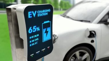 Elektrikli araba EV şarj kablosu ile şarj olmak için şarj istasyonuna bağlı. Geleceğin yenilikçi EV arabası ve enerji sürdürülebilirliği. Akıllı ve fütüristik ev enerjisi altyapısı. İnceleyin